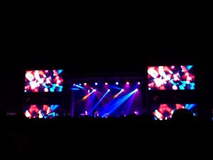 Oameni dansând pe o scenă iluminată la un festival.