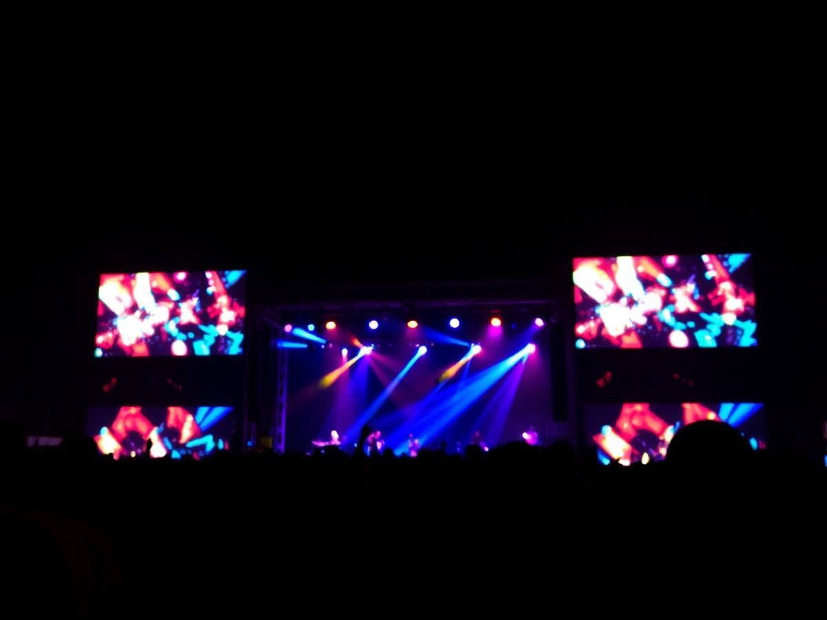 Oameni dansând pe o scenă iluminată la un festival.